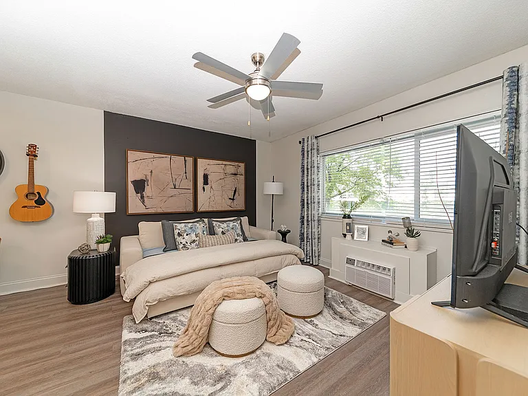 Spacious open living & sleeping area with hardwood-style flooring & ceiling fan