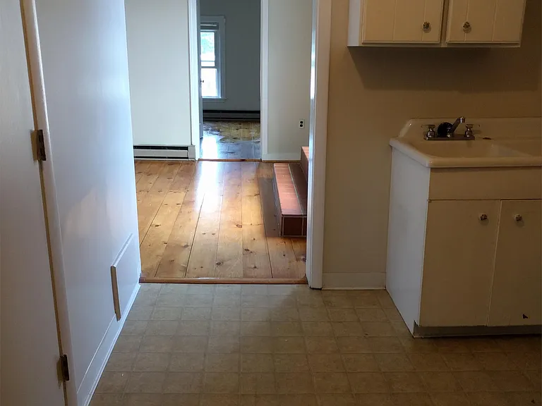 view from bedroom doorway, through kitchen, living room to front room