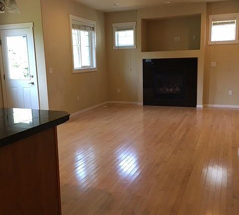 Living room with fireplace .Hardwood floors. Through the doo