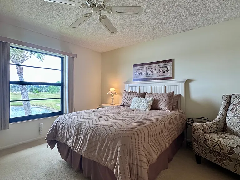 Spacious Primary Bedroom w/ stunning expansive lake & golf course views + a HUGE walk-in closet & walk-in shower!