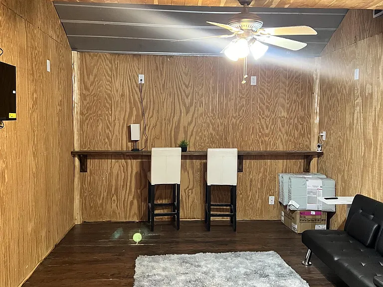 Versatile bonus room with wood paneling, ceiling fan lighting, and a built-in counter for work or casual seating.