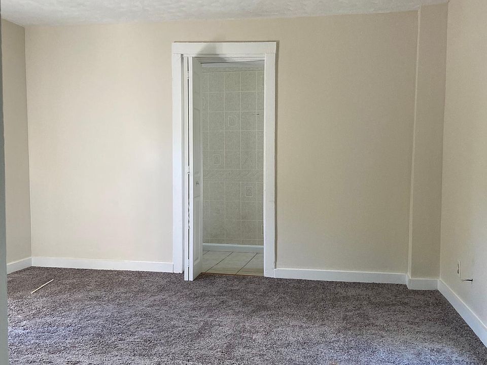 View from kitchen into living room, entrance to apt is on the left. New carpet has been installed and walls have a fresh coat of paint.