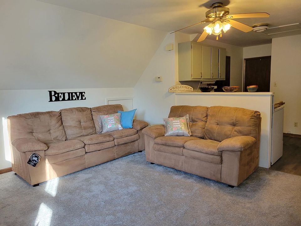 Living Room, showing couch and loveseat and upper cabinets in kitchen