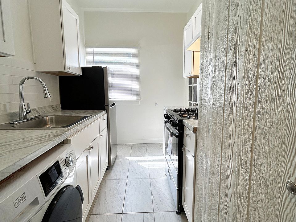 Kitchen view from Hallway. NEw Washer/Dryer, cabinets, sink with retractable sprayer, gas stove/over, refrigerator and flooring.