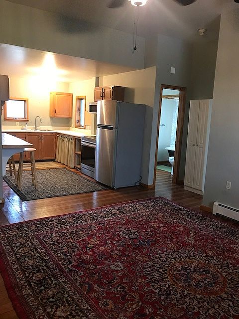 Livingroom/kitchen. Doorway to Bathroom, oriental carpet, baseboard radiator 10-foot ceiling shown.
