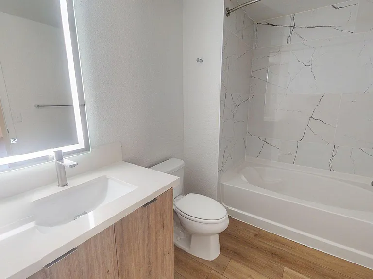 Apartment Bathroom with large soaking tub, large Sink, LED vanity mirror and wood-style flooring