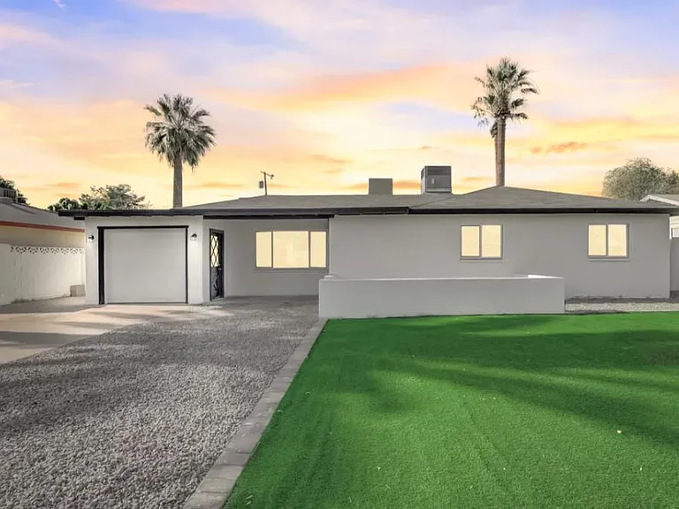 Single-story home with a wide driveway, attached garage, and low-maintenance front yard with a privacy wall.