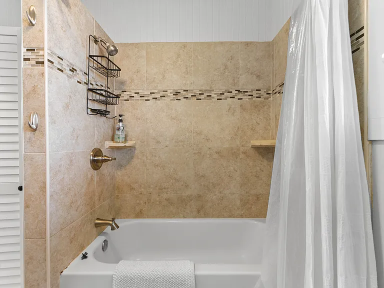 Large bathroom with high ceilings, ceiling fan, window, vanity with storage, bidet, bathtub and shower.