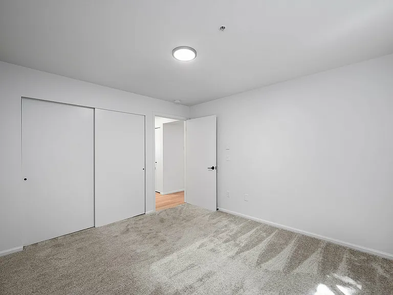 Experience the potential of this bright, minimalist bedroom with ample storage.