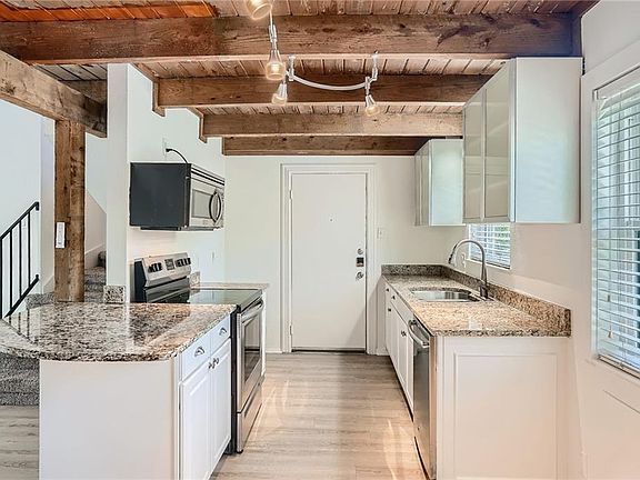 Kitchen with access door to stairs down that lead to back parking lot. granite countertops, stainless steel appliance. Refrigerator is in kitchen