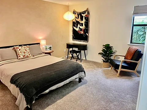 Primary room on the main floor with queen bed, reading nook, and desk area