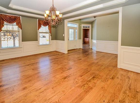 Dining room has a tray ceiling and wainscoting