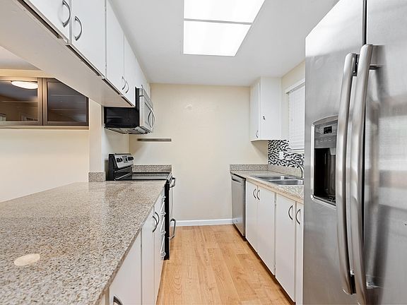 Kitchen with granite counters, cabinet organizers, dishwasher, microwave, and refrig with ice and water in door.