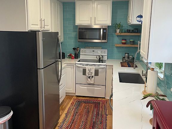 Updated galley kitchen with newer appliances, quartz countertops and a big basin sink