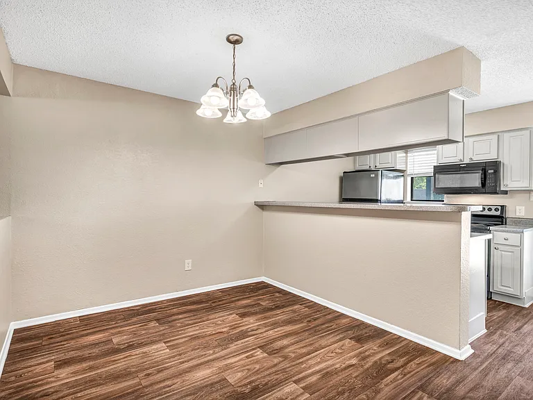Open kitchen with wood-style flooring and updated lighting.