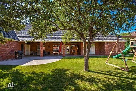 Large covered patio in tree covered backyard.