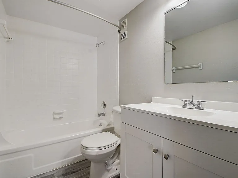 Modern bathroom with sleek white fixtures, a spacious tub, and elegant vanity, offering a clean and refreshing space.
