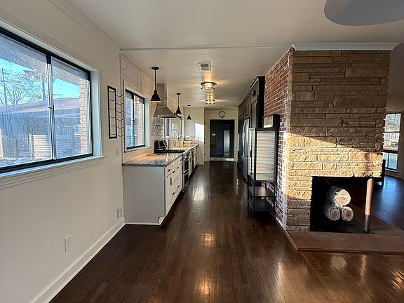Kitchen/Dining/Living Room- 
Original Oak Hardwood Floors, Linear Stone Gas Fireplace, Exposed Brick in Kitchen, Black Metal Grid Windows.