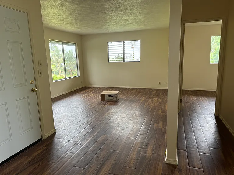 Living room on left. Ceiling fan to be installed. Hallway leading to bedroom one is on the right.