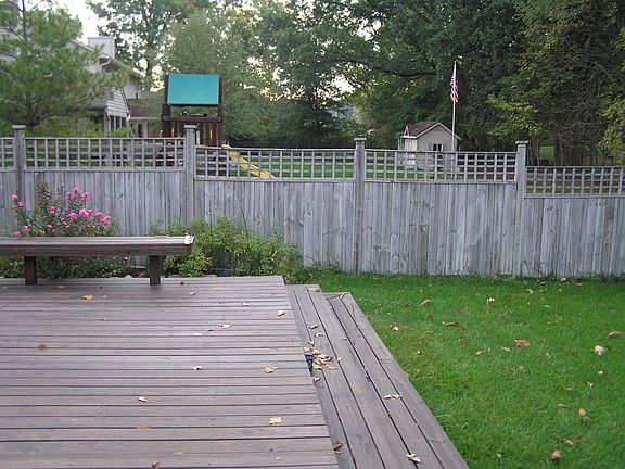 Large deck and fenced yard with tree lined back yard