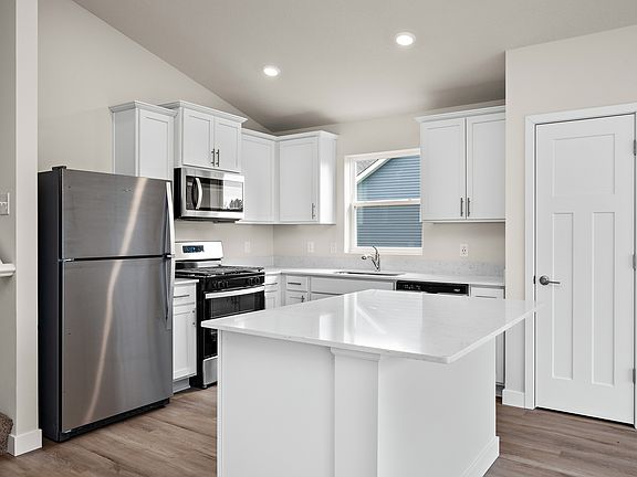 The kitchen has stainless steel appliances and plank flooring.