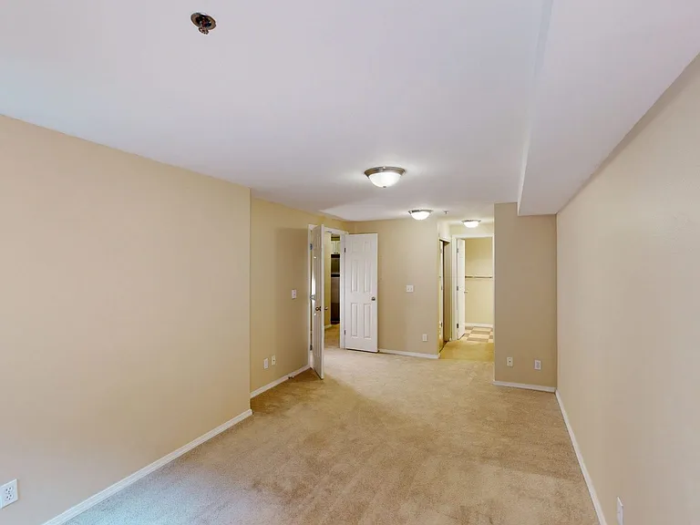 Spacious apartment bedroom with attached bathroom and plush carpet flooring.