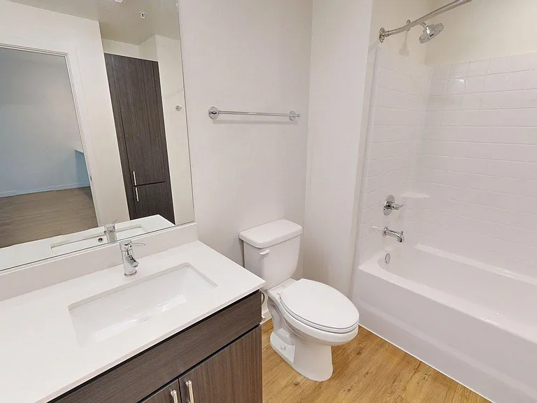 Apartment bathroom with soaking tub and wood style floor.