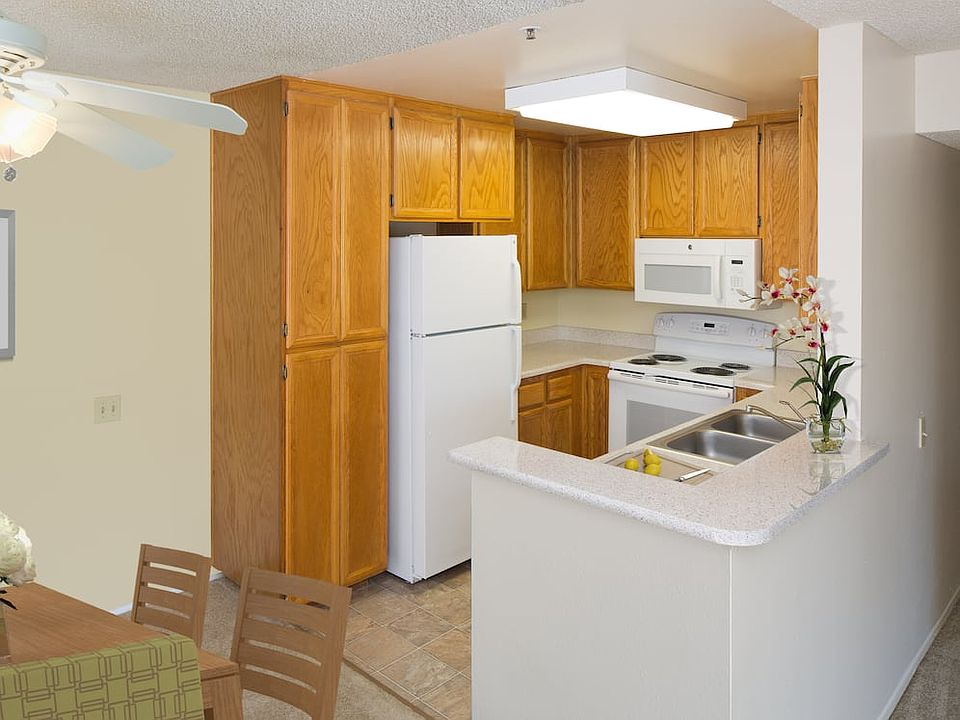 Classic Package kitchen with oak cabinetry, beige speckled laminate countertops, tile flooring, and white appliances