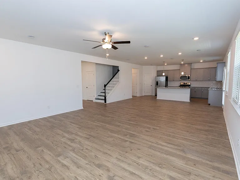 Open and airy kitchen equipped with a refrigerator, sink, and ceiling fan.