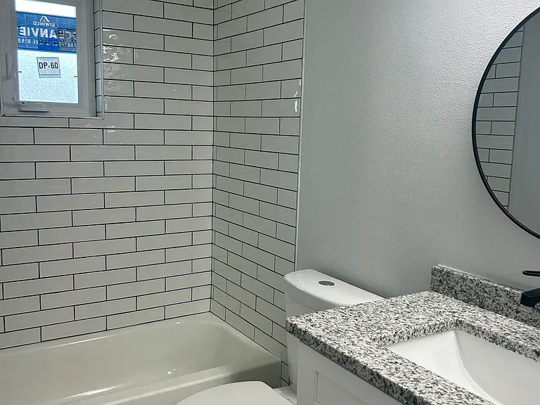 Newly updated bathroom with bright lighting, granite counter tops and new cabinet with black hardware.