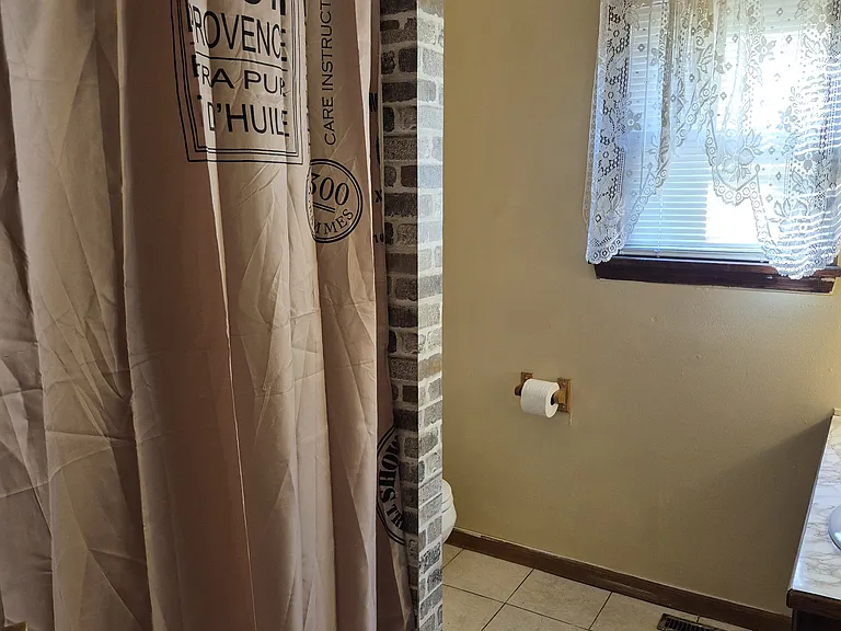 View bathtub with shower curtain from kitchen doorway