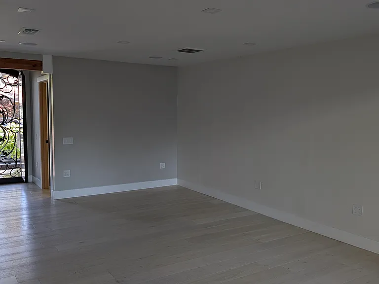 View of living room (comes with TV mount) pre-installed. The glass pane of the front door opens to allow a cool breeze across the house while leaving the door closed.