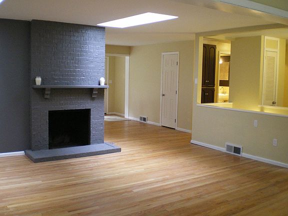 Wood burning fireplace, multiple windows, and dual skylights in living room.
