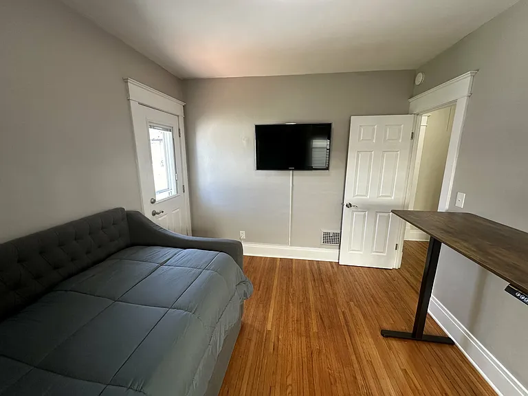 Alternate view of the third bedroom with workspace and wall-mounted Smart TV.