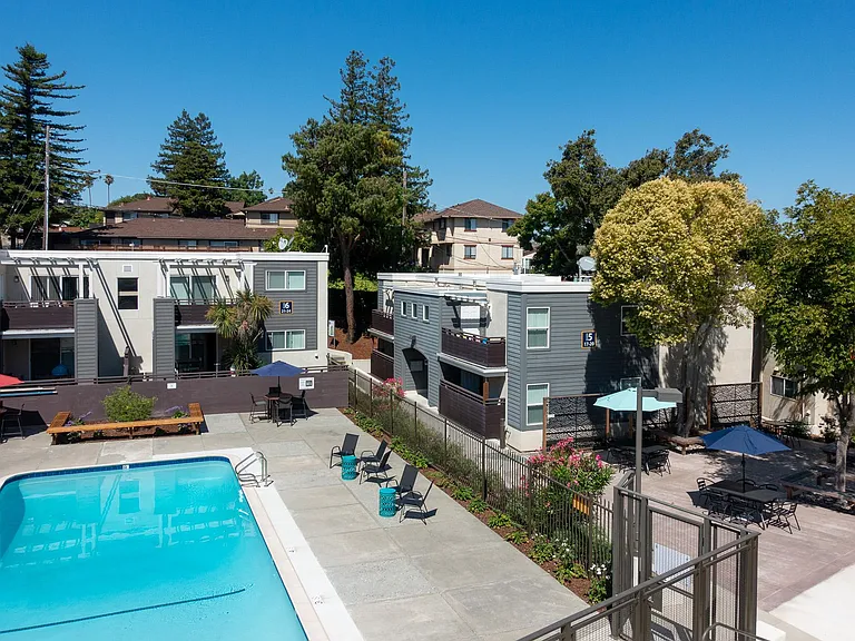 Swimming pool and patio area with tables to the right