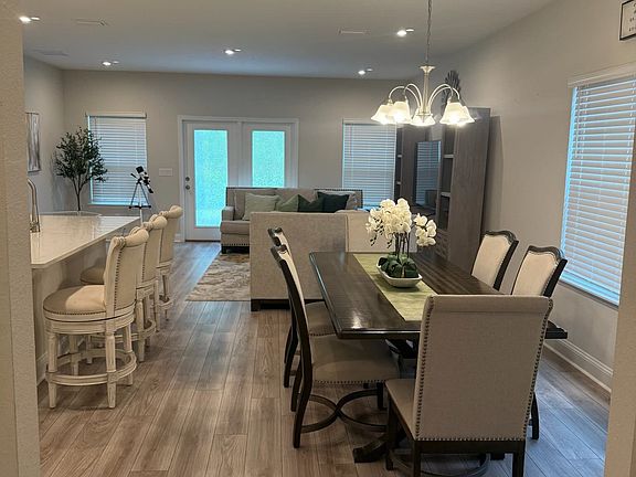 Spacious dining area with modern lighting and open flow to kitchen and living spaces.