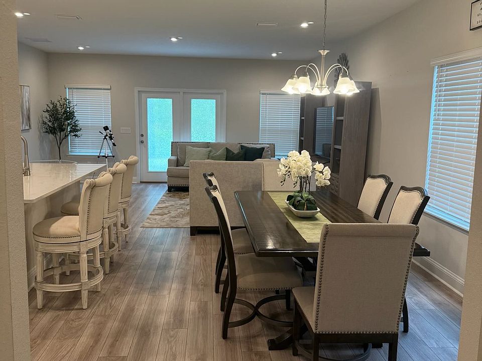 Spacious dining area with modern lighting and open flow to kitchen and living spaces.