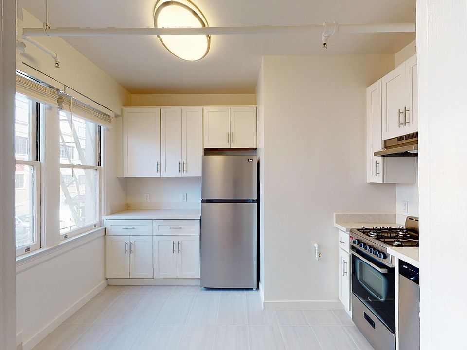 Modern kitchen featuring stainless steel appliances, cabinetry, and large windows for natural light. Clean and spacious design.