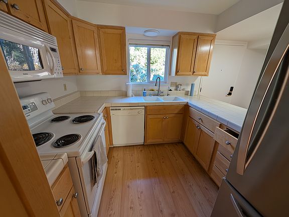 View into kitchen. Shows microwave over stove, dishwasher, and refrigerator.
