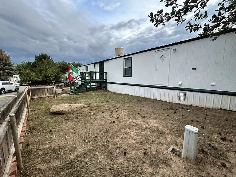 Front and back yard with sprinklers and small firewood pit on concrete slab