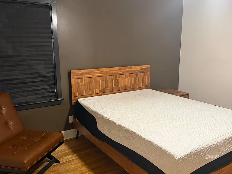 Furnished bedroom with a platform bed, hardwood floors, and a window with blinds for privacy and light control.