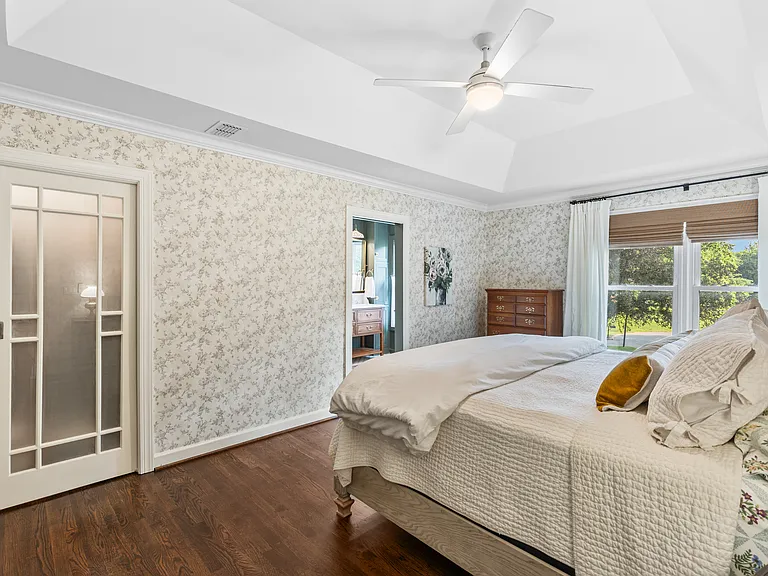Primary bedroom with a comfortable King bed, room-darkening shades, a ceiling fan, closet, and ensuite bathroom.