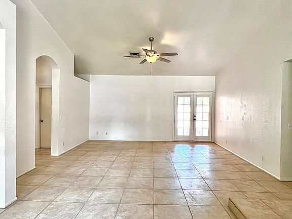 Spacious living room with fan & vaulted ceiling.