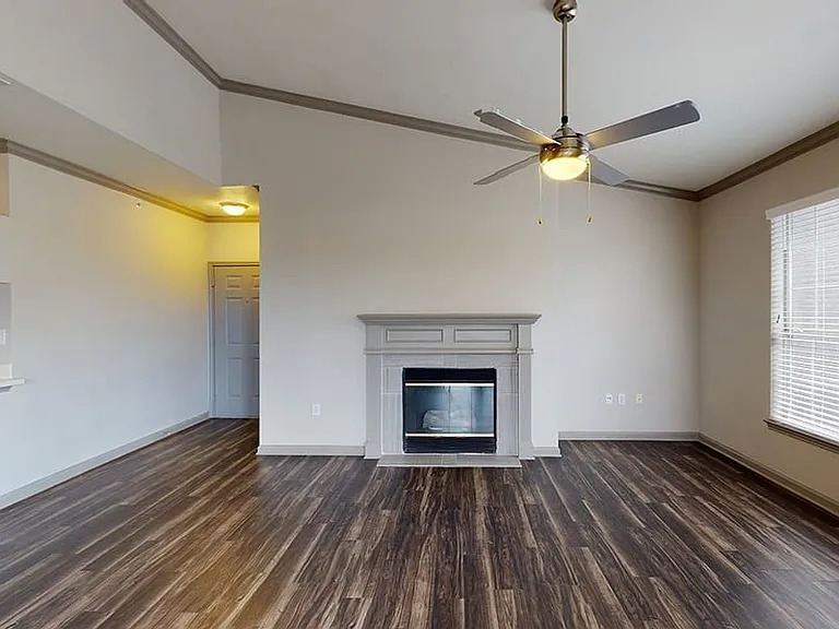 Apartment living room with wood-style flooring and fireplace in select homes.