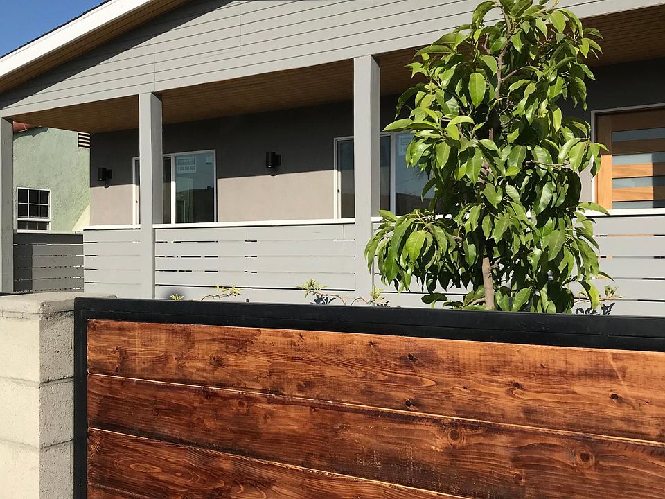 Front of the house w/ stained redwood fence & tree