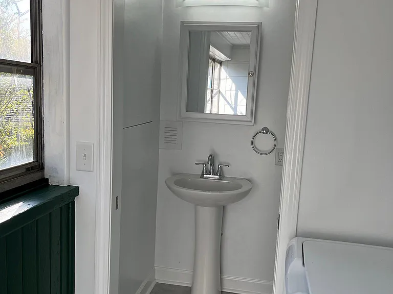 Half bath has a pocket door between it and the laundry room and a large rain glass window to the left as you enter the room.
