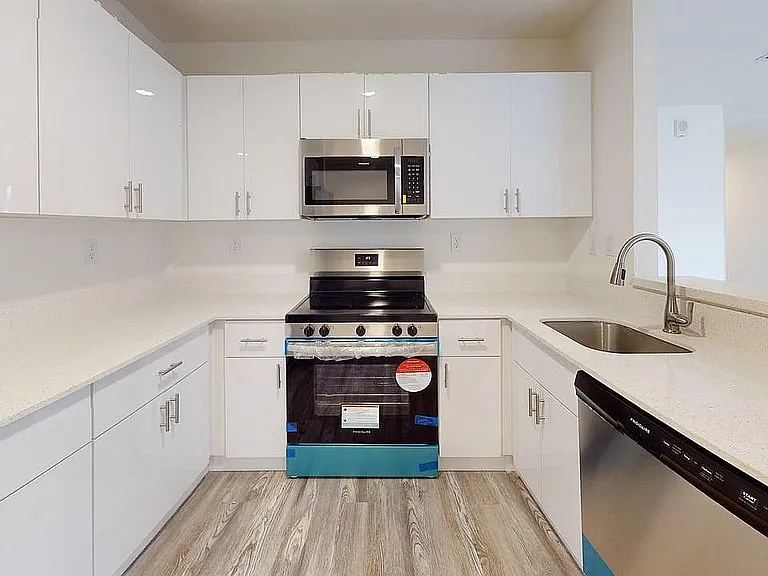 Sleek modern kitchen with stainless steel appliances, elegant white cabinetry, and polished countertops, offering a bright and inviting culinary space.