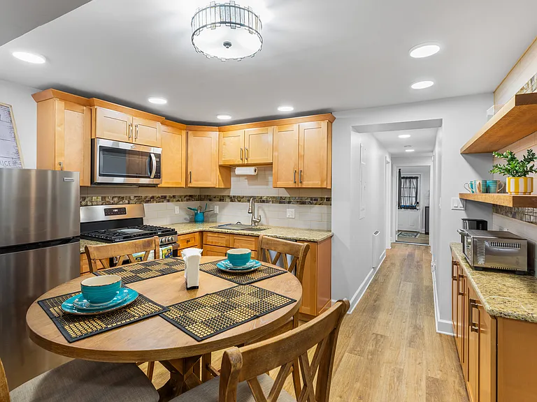 Modern Kitchen with brand new appliances and counter size table with chairs. Kitchen is fully equipped for cooking.