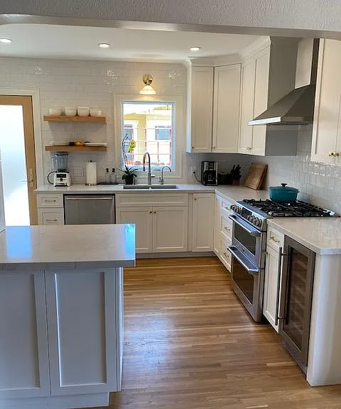 GE Cafe stove/double oven and hood next to wine fridge