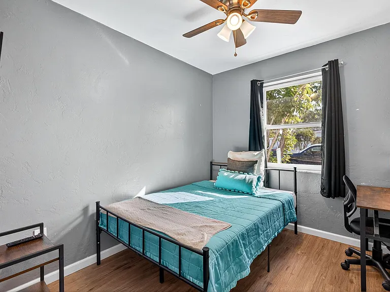 Room 2 featuring full-size bed, dedicated workspace, wall-mounted television & portable closet for clothing & personal items.